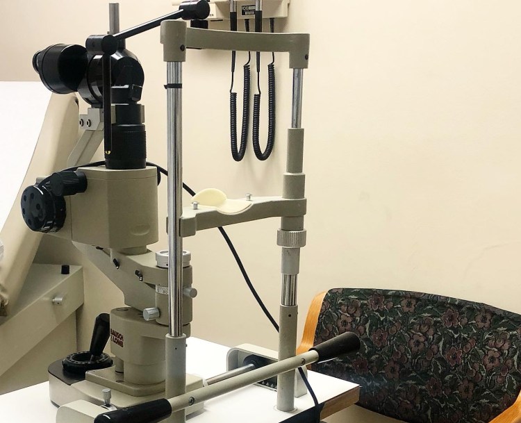 Slit lamp on a small table with an empty chair behind it.