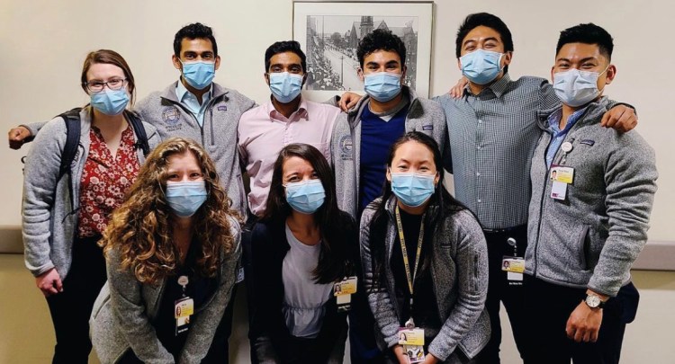 A group of medical student volunteers pose together with their arms around each other.