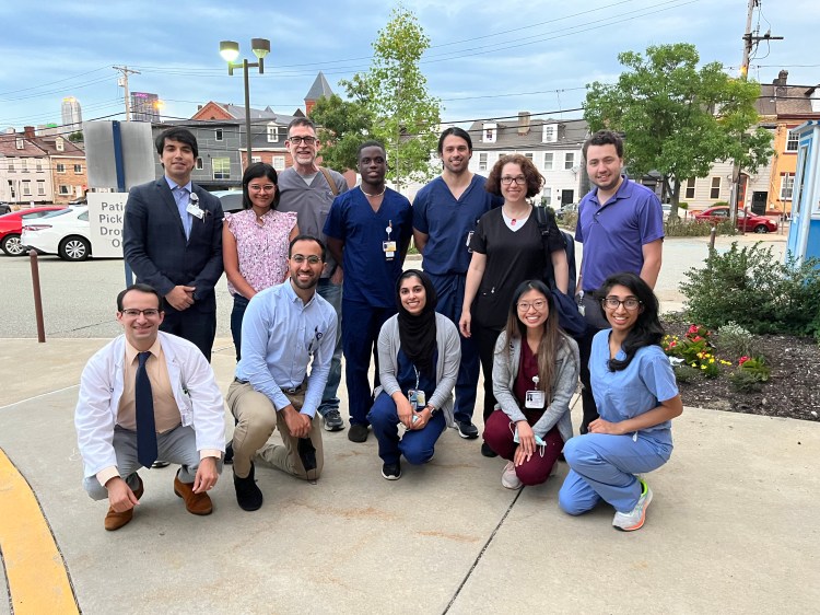 Medical student volunteers pose together after a GES mission, some are wearing scrubs, some are wearing business attire. 